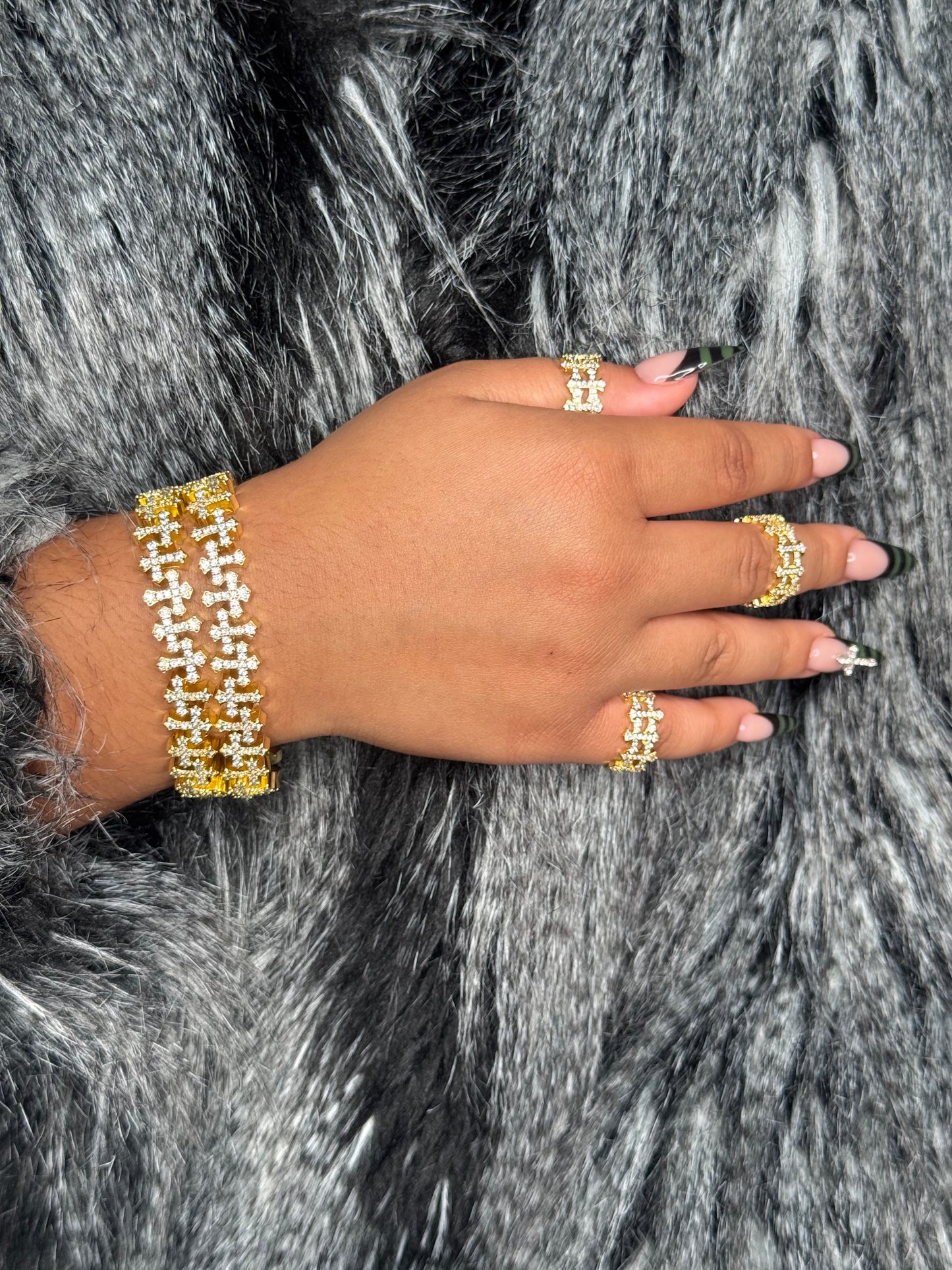 Worn: THE ENIGMA checkered open cross statement ring worn on finger in gold and veil gold bracelet on wrist